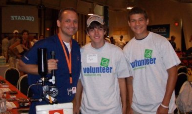 TeamSmile co-founder William Busch, DDS, MAGD, with a pair of volunteers from Naperville, Illinois at an event at the Chicago Bears training camp. | Credit: © TeamSmile
