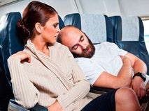 Image of a person sleeping on the shoulder of the stranger next to him on a plane