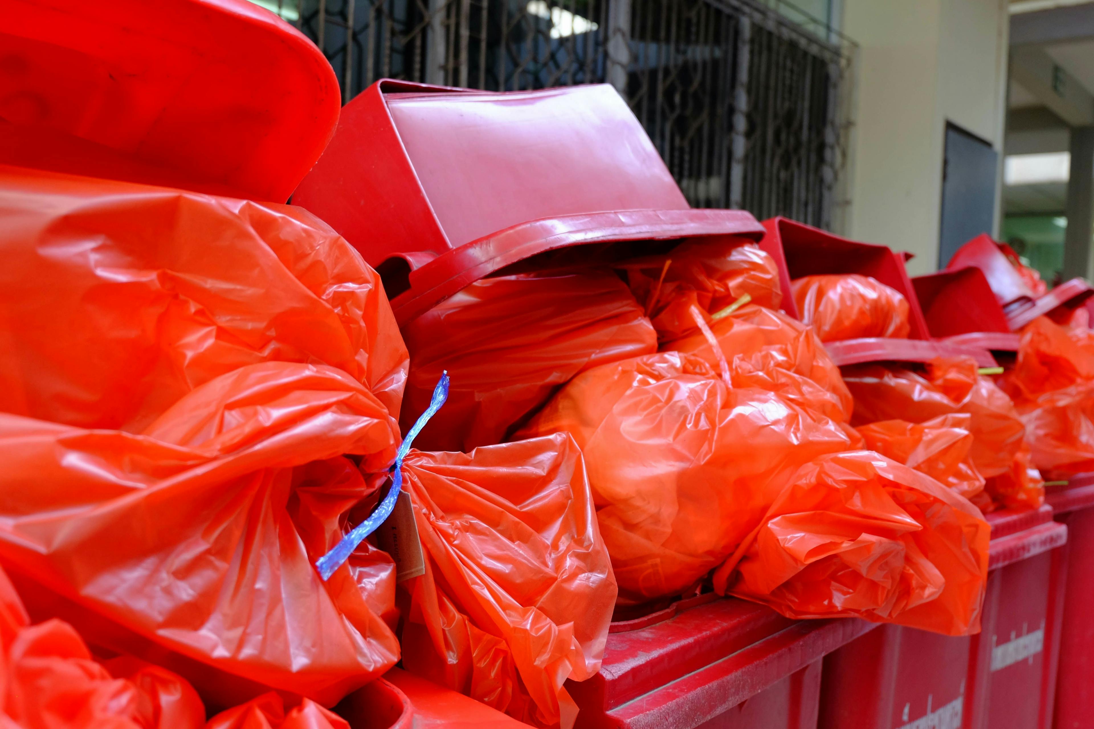 Red trash cans overflowing with red bags of biohazardous waste